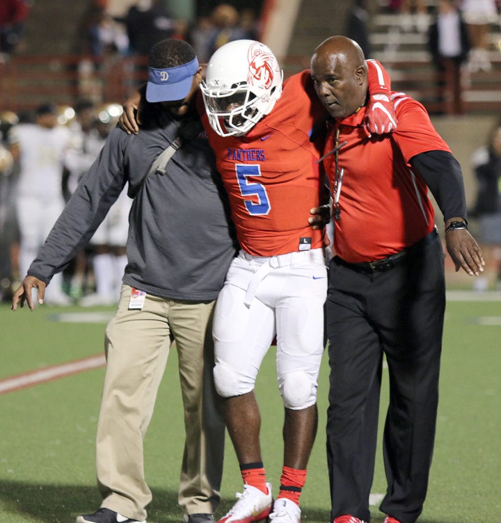 Duncanville Quarterback Jaylin Nelson is supported by an athletic trainer and Coach Reginald Samples as he makes his way off the field Friday, October 21, 2016. Nelson suffered a broken femur bone during the first quarter of the Suburban Bowl versus DeSoto. (Jose Sanchez/Duncanville High School)