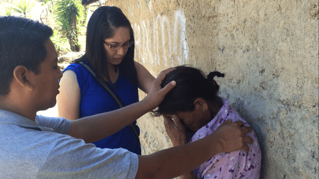 Cardenas prays with a resident in Honduras.