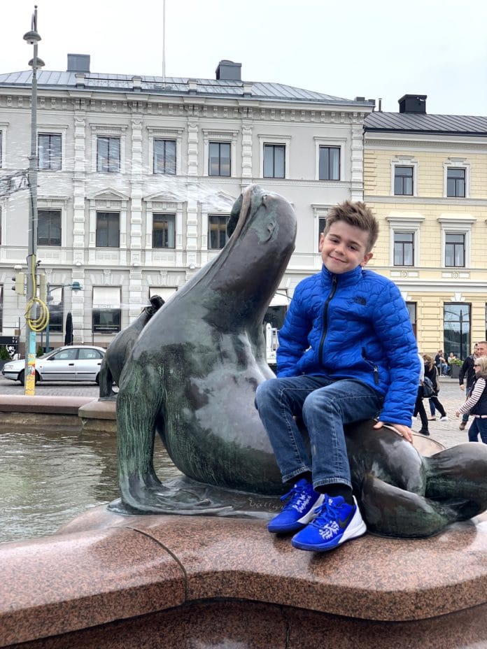 boy sitting on sea lion statue in Finland