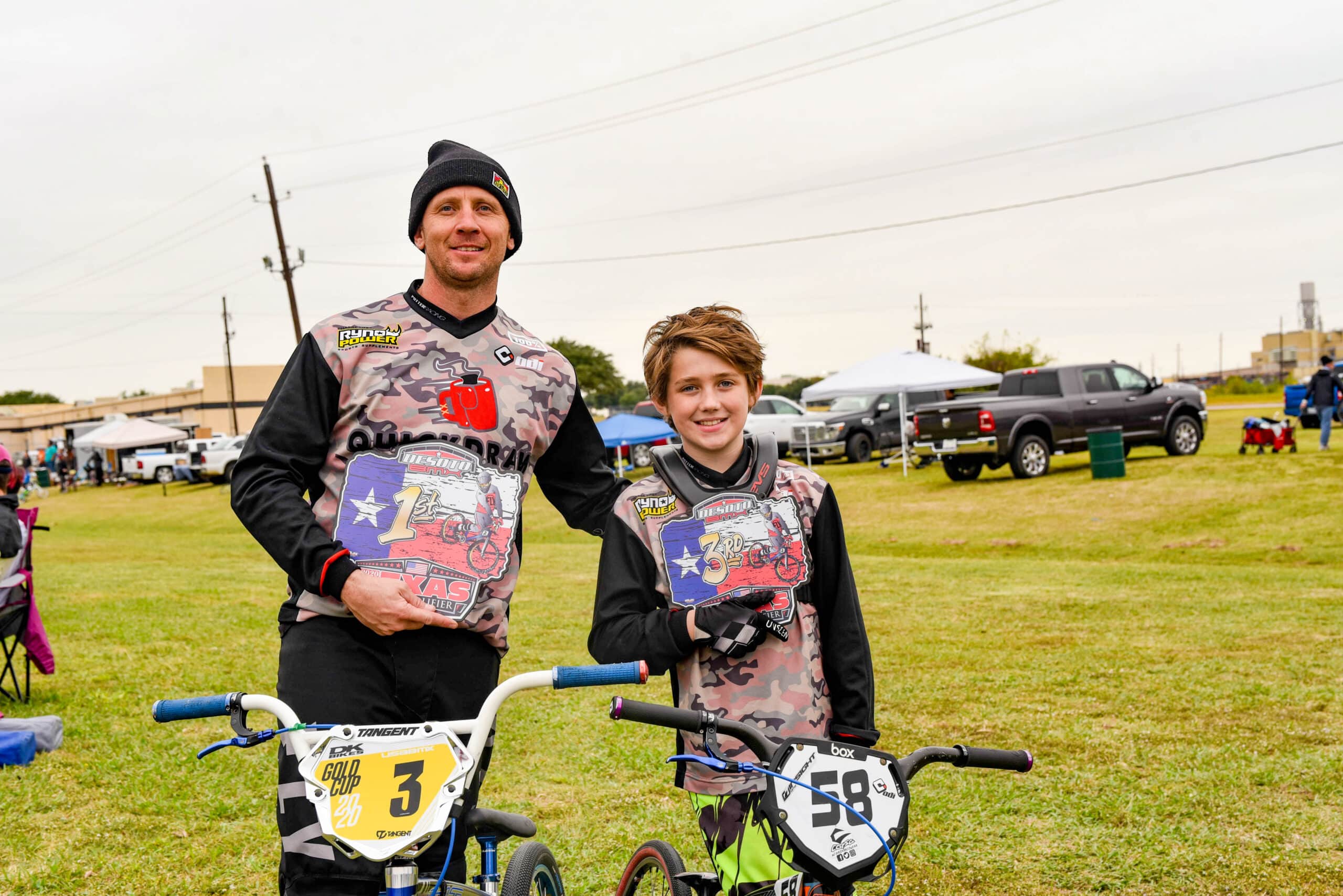 Man and boy showing trophies from BMX race