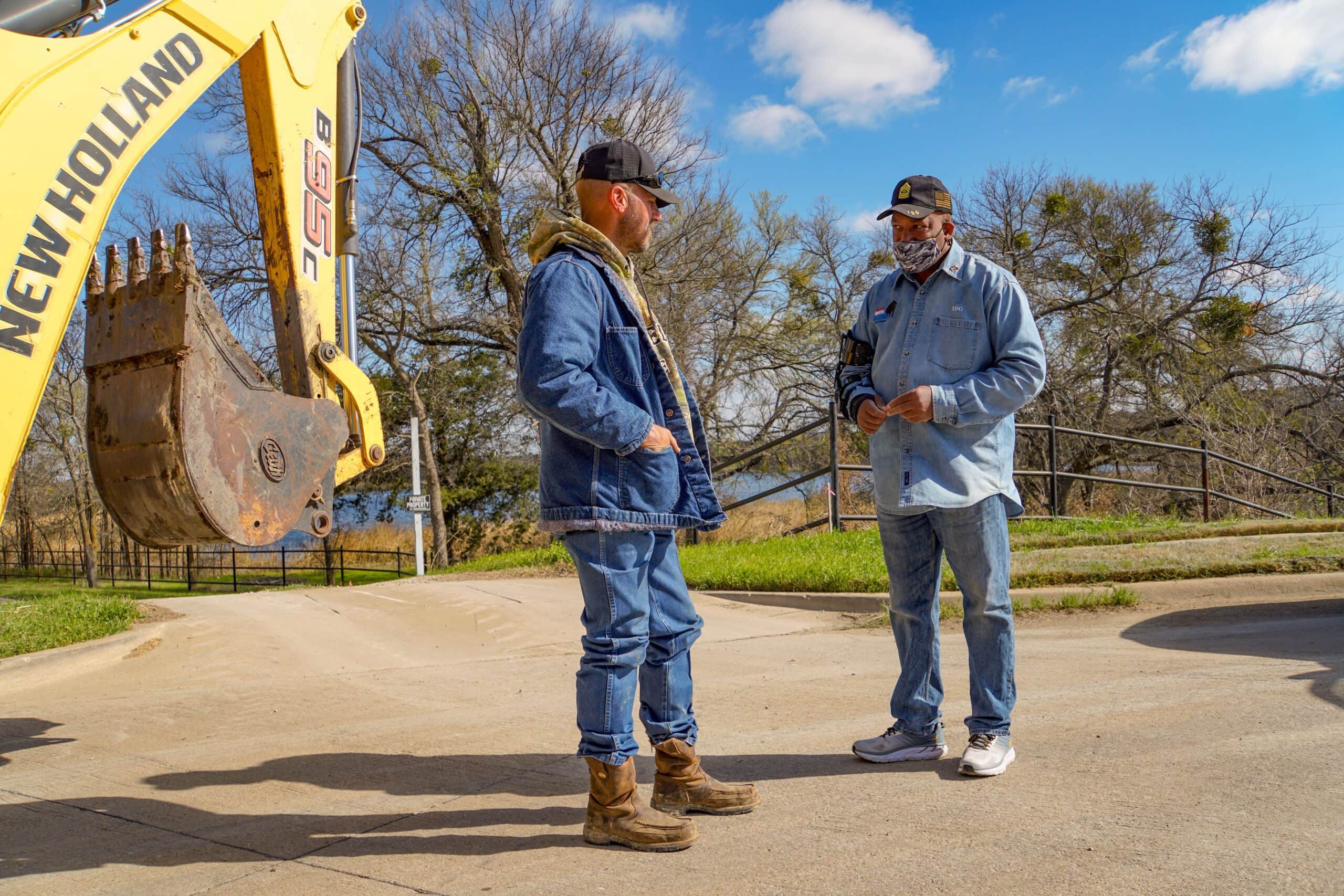 Two men talking by backhoe