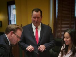 Two men with a woman signing document