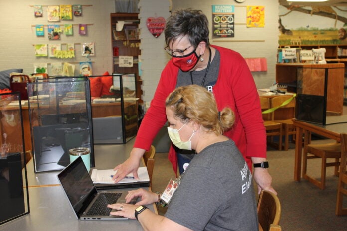 two women use laptop