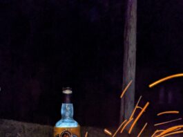 Bottle of black button bourbon by firepit