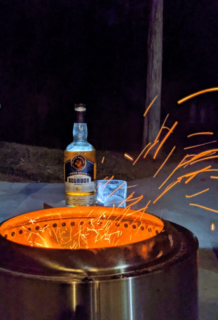 Bottle of black button bourbon by firepit