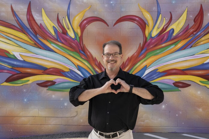 man standing in front of heart mural