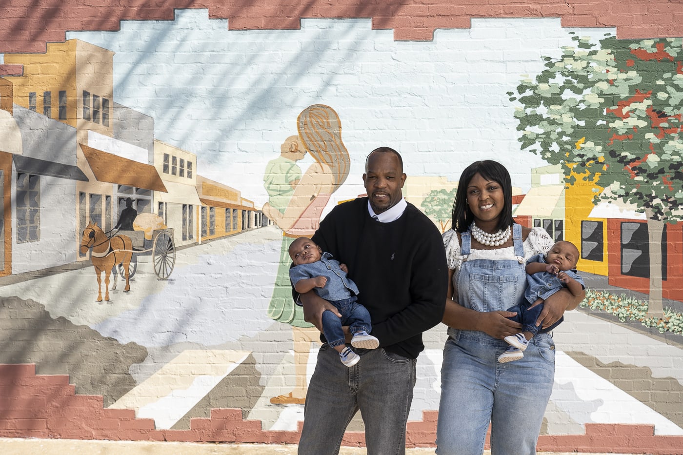 couple with baby in front of mural