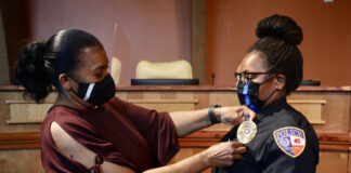 Former Cedar Hill Scholar, Tiffany Atkinson, Sworn In As CHISD Police Office woman placing badge on Officer