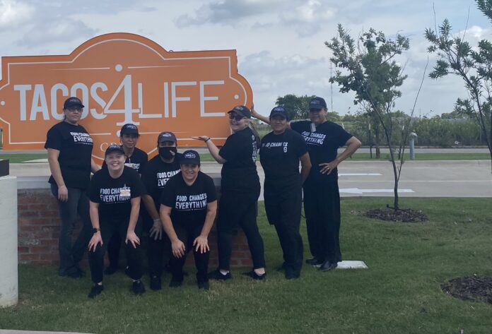 Tacos 4 Life staff in front of sign