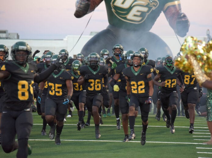 football players run onto field