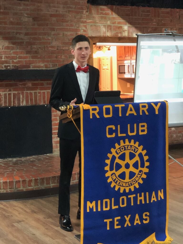 young man in front of rotary flag