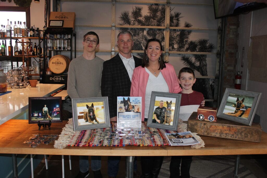 family standing behind photos of dog