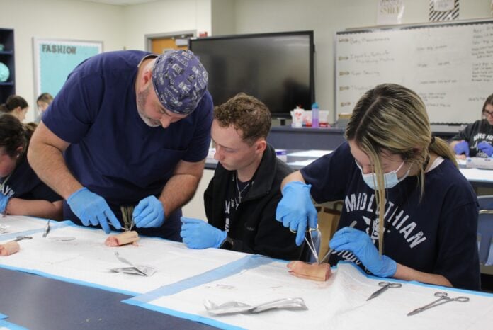 doctor shows kids how to suture