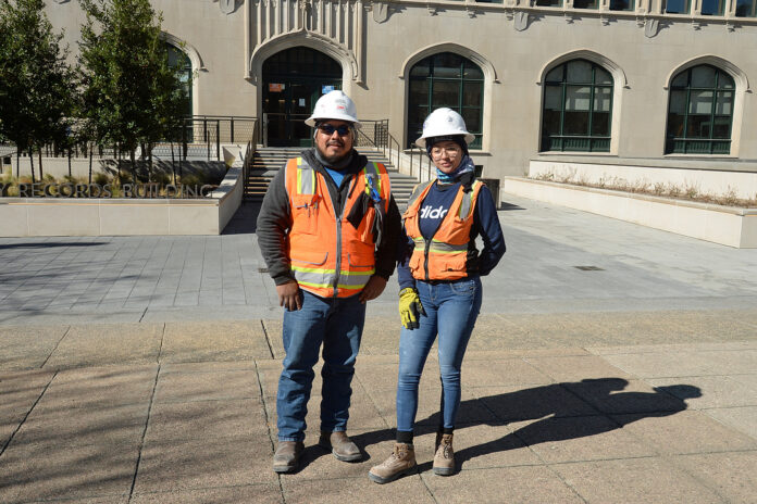 man and woman in hard hat and orange vest