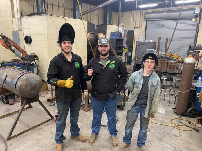 three guys wearing welding helmets