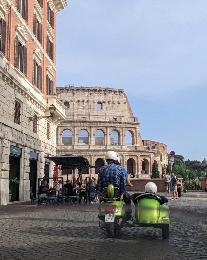 Vespa with sidecar view from behind with Colosseum