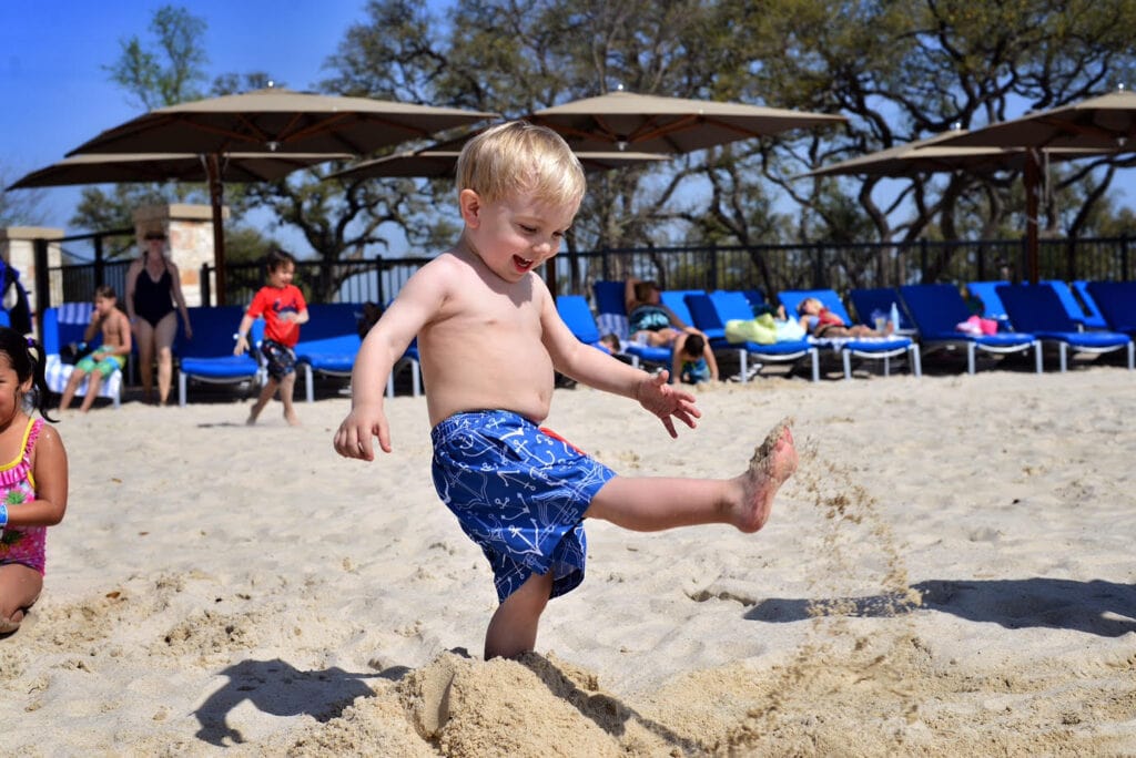 boy kicking sand on beach