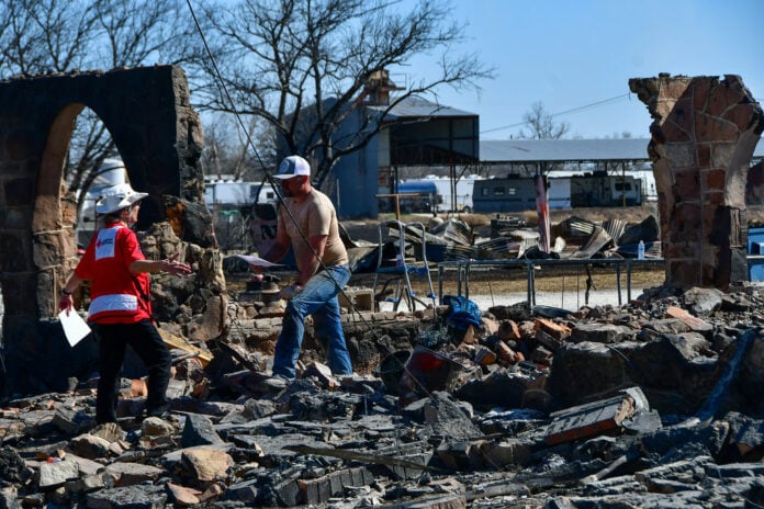 people walking through fire damaged ruins