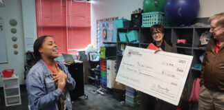 Cedar Hill Grad’s Return Creating Special Opportunities teacher with check