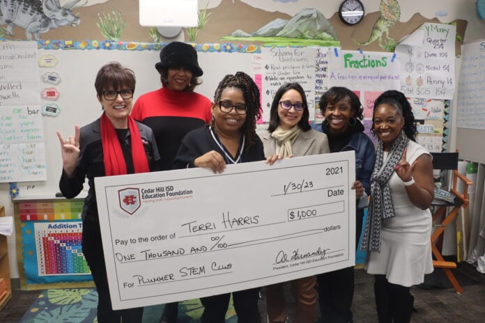 adults and students holding cardboard check