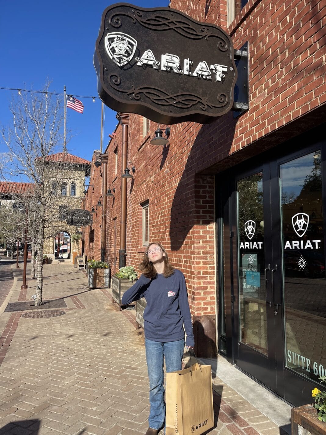 girl standing below Ariat store sign