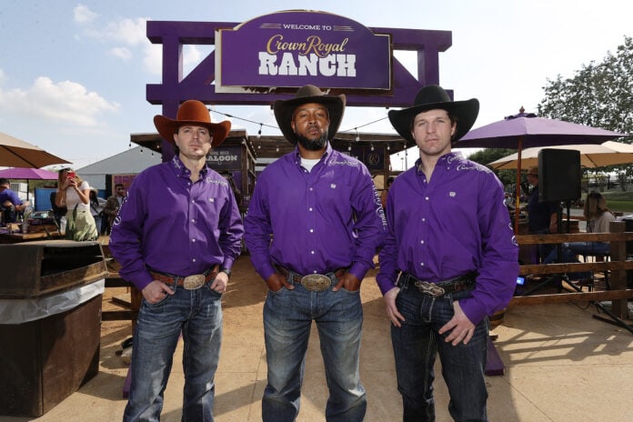 three cowboys in front of crown royal ranch sign