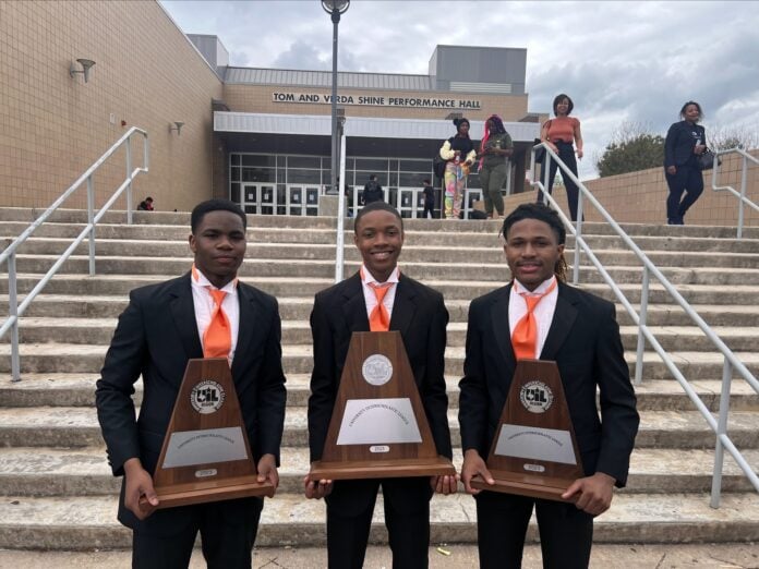 three high school males holding UIL trophies