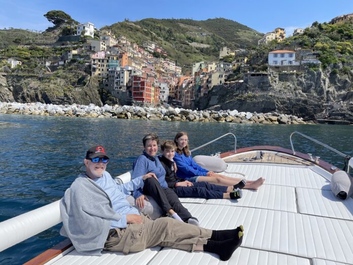 family on a boat with an Italian village in the background