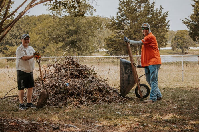 men with wheelbarrow and brush pile