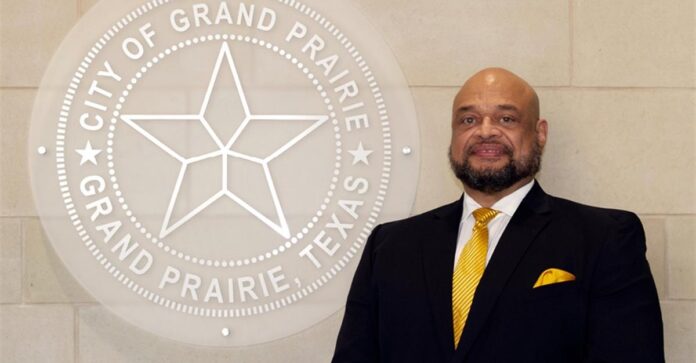 Bill Hills in front of Grand Prairie logo