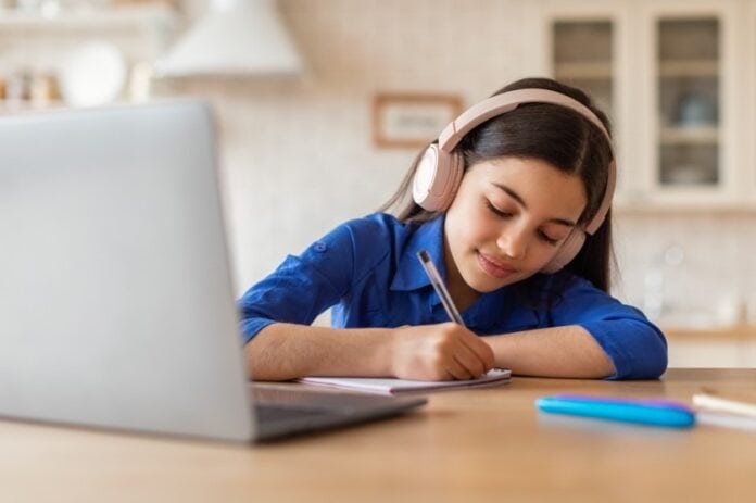 girl wearing headphones by laptop
