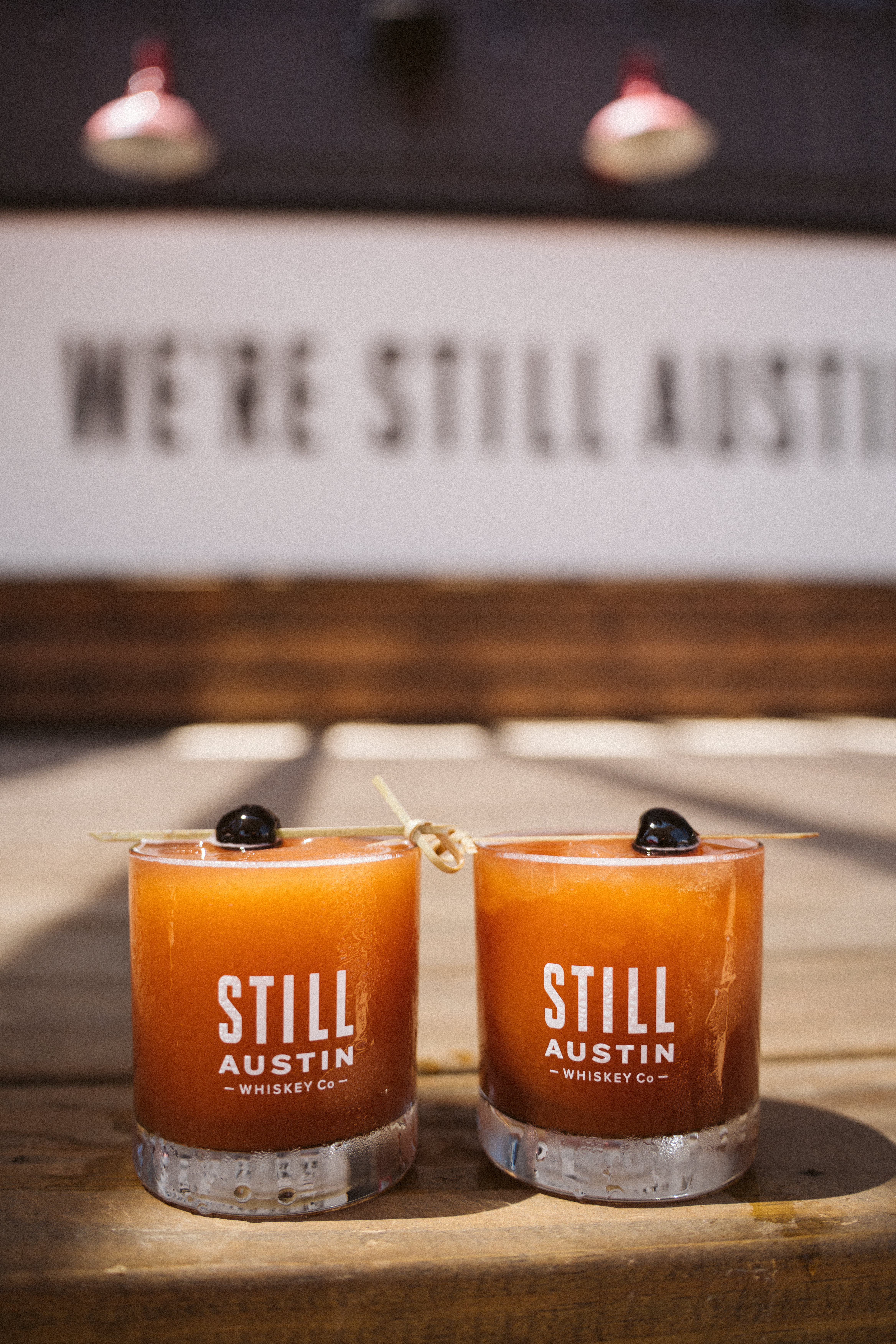 two Still Austin glasses with orange cocktails