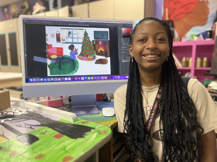 12.13 Christmas Art Contest Zariel Williams with Christmas card design on computer monitor