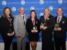 three ladies and two men standing with trophies