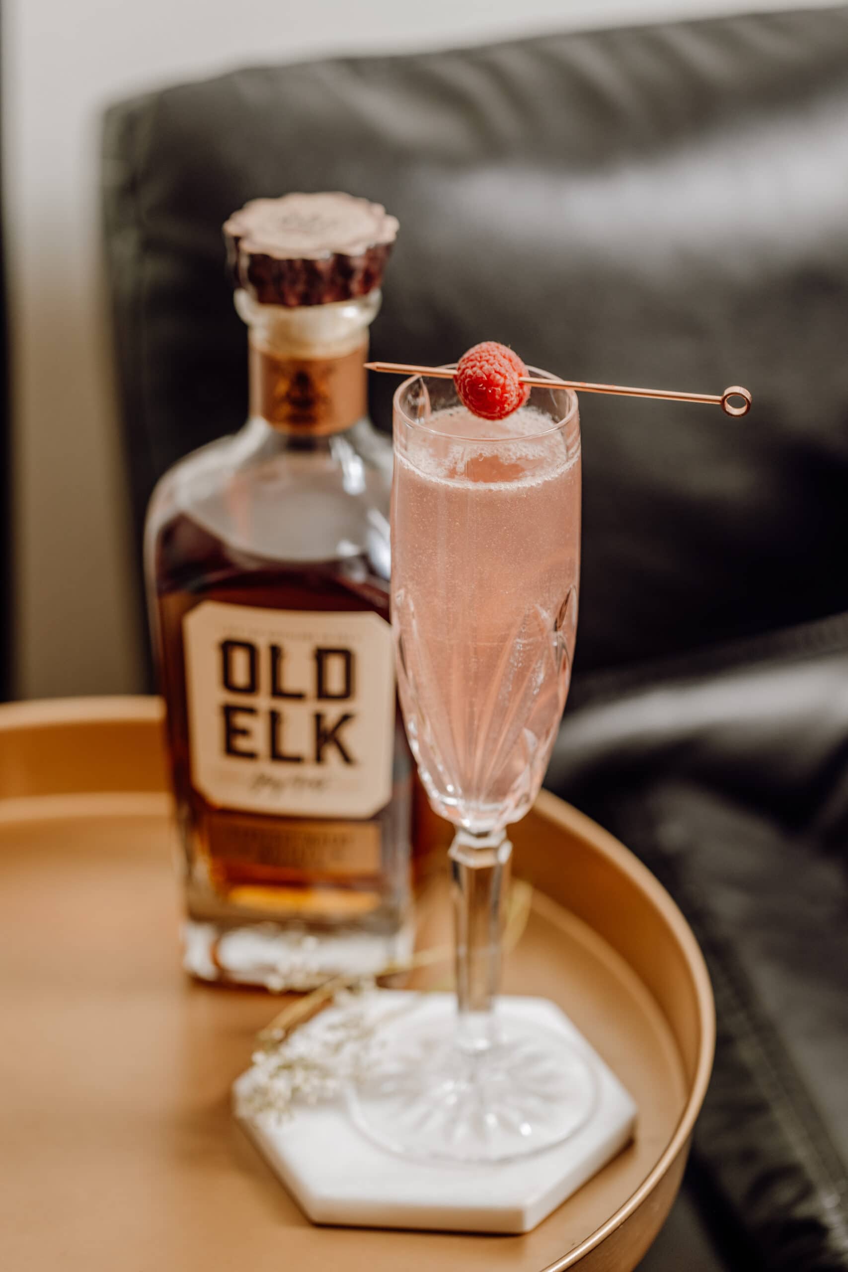 Old elk whiskey bottle with champagne glass and pink drink