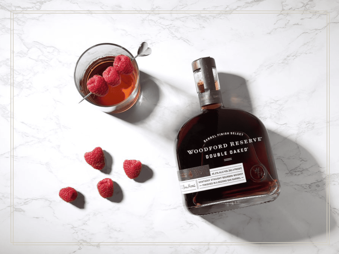 raspberry garnished cocktail with Woodford Double Oaked bottle