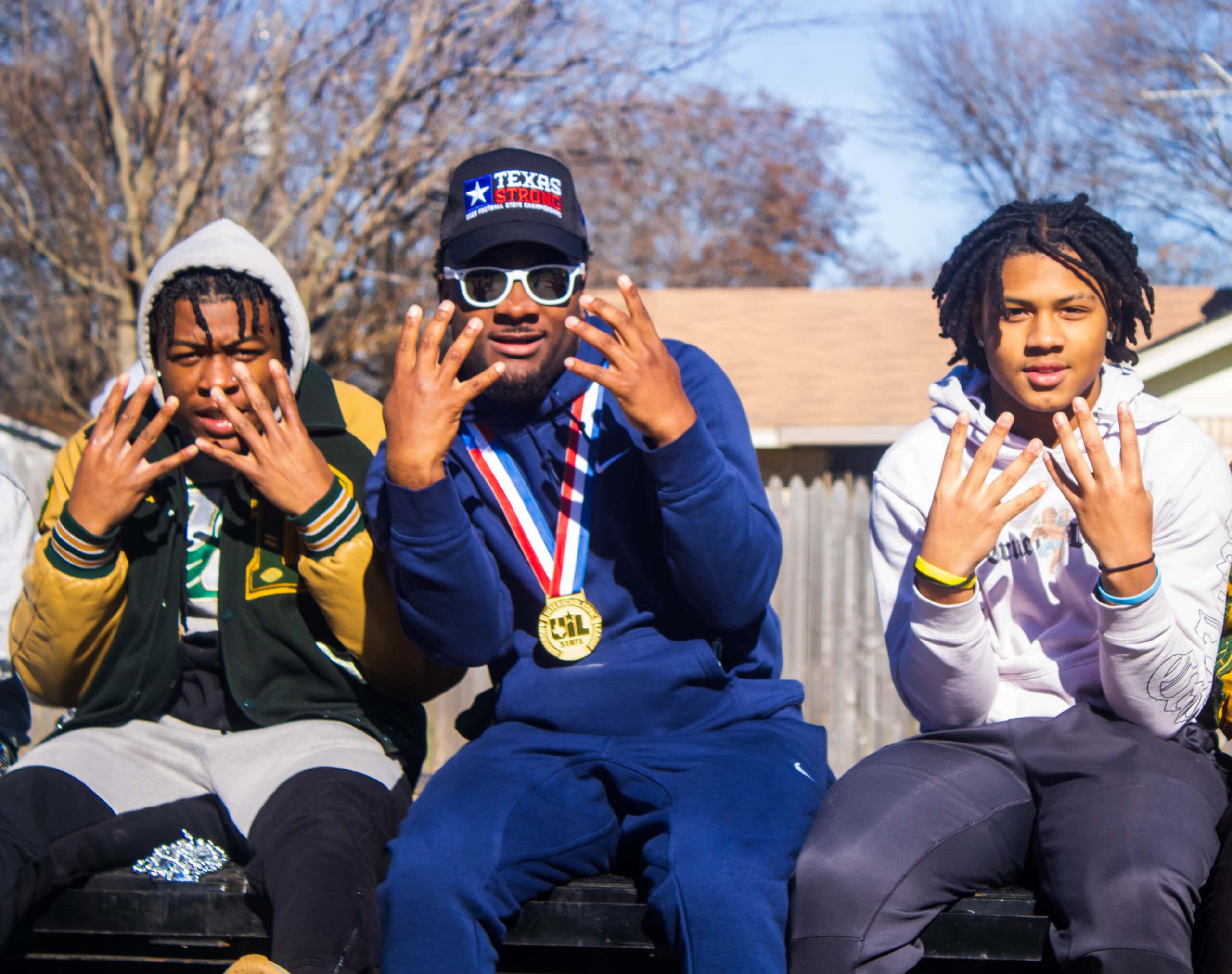 three DeSoto football players celebrating the Eagles' state championship at a parade, (from left) Jaylin “Hawk” Jones, Marvin Duffey Jr,  Nicholas Hamilton.