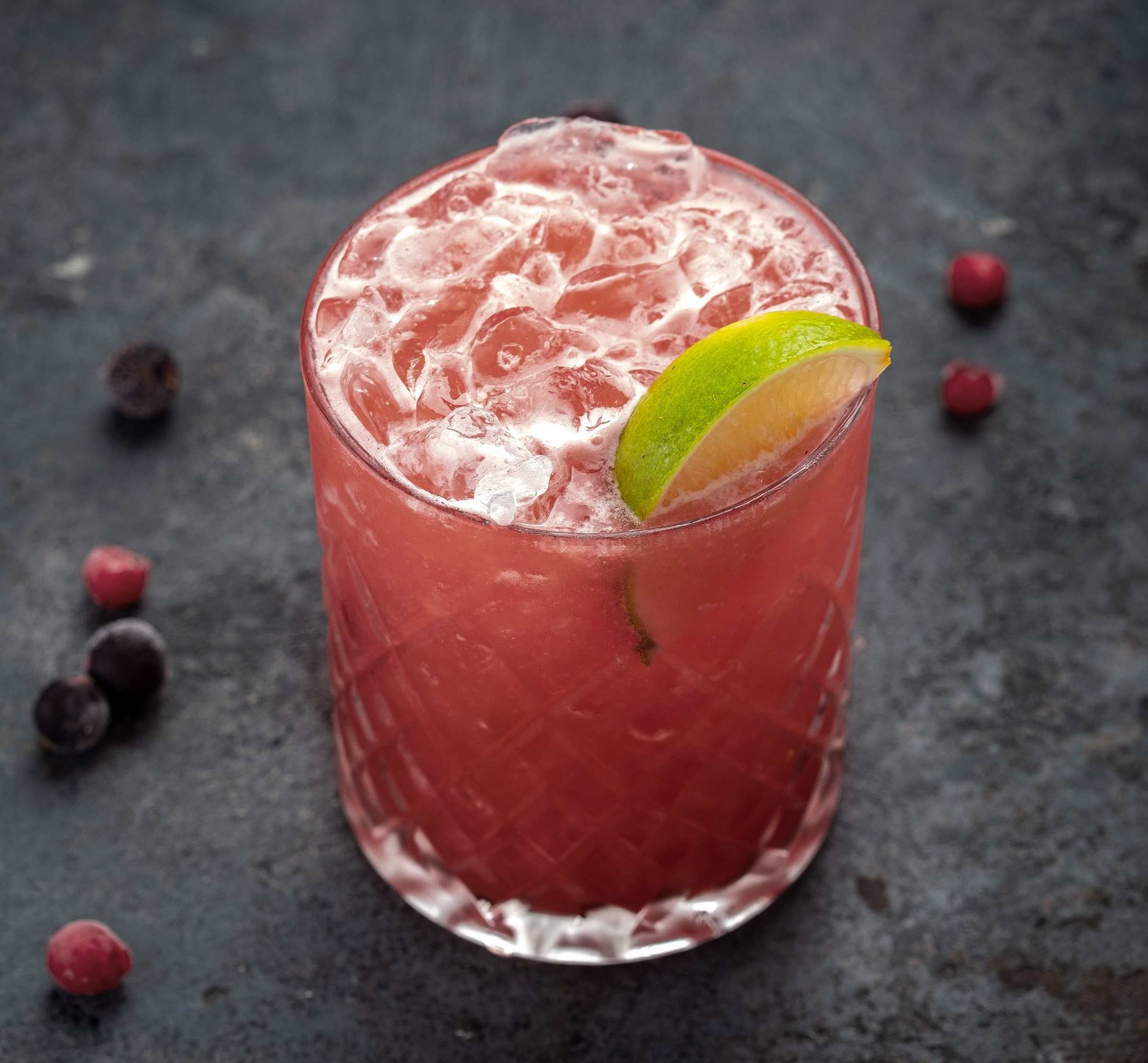 pink cocktail in rocks glass with lime garnish