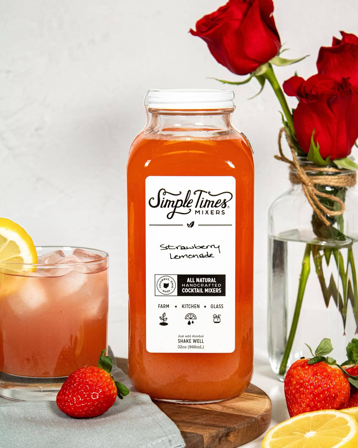 bottle of strawberry lemonade with drink in glass and roses in vase