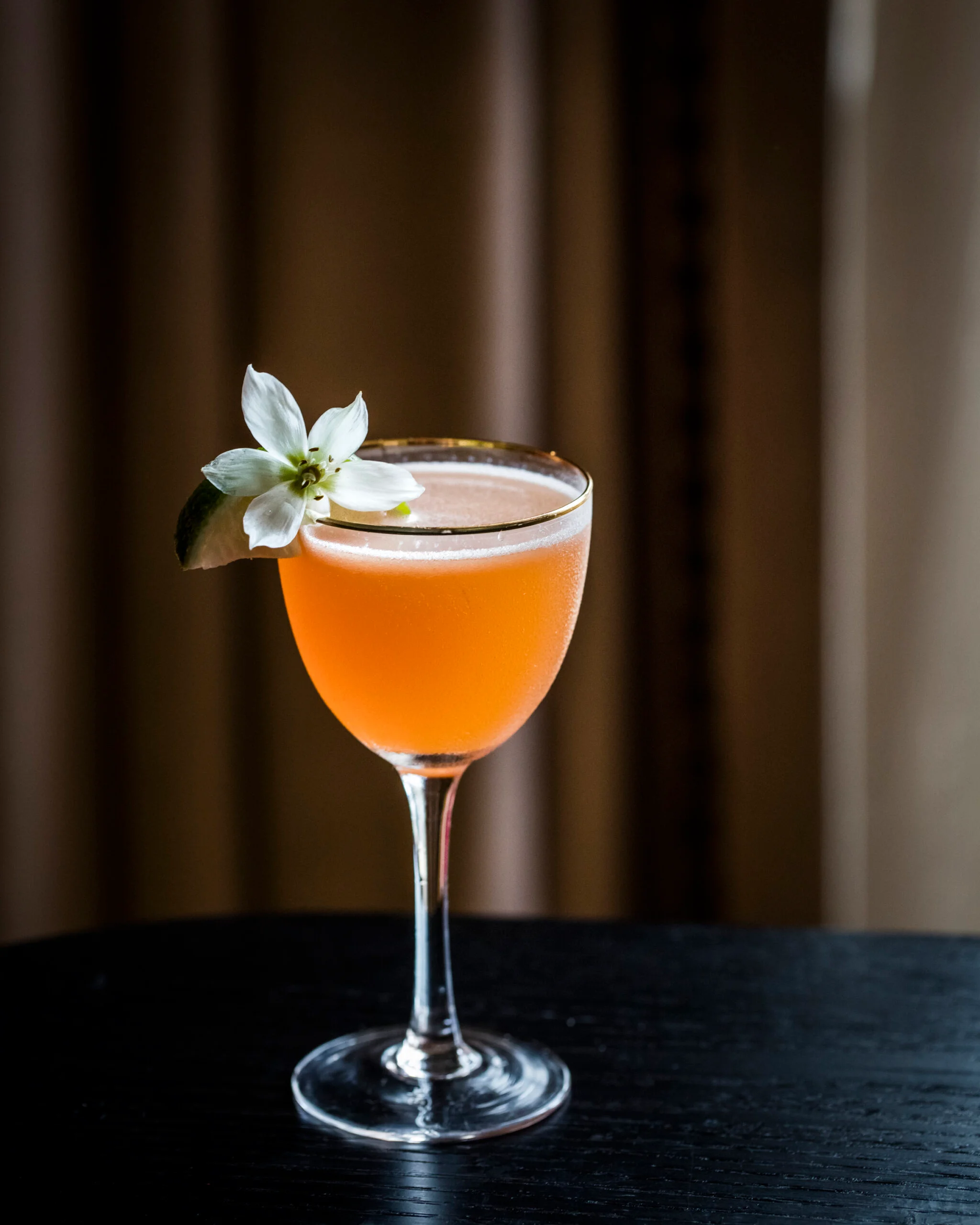 orange cocktail with flower garnish
