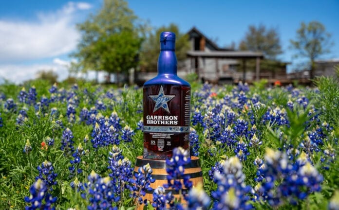 Bottle of bourbon surrounded by bluebonnets
