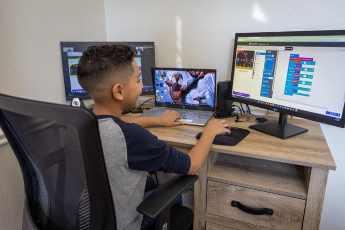 kid at desk with computer screens